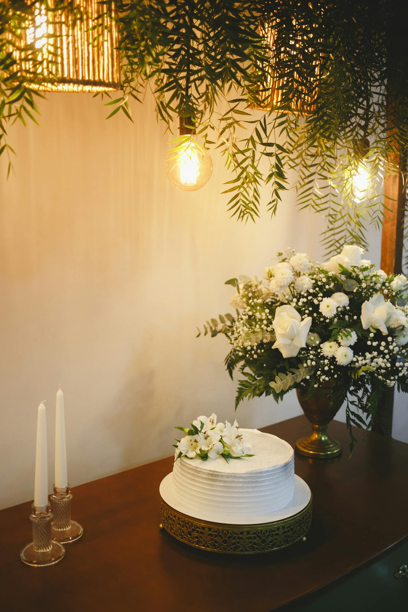 A beautifully decorated wedding cake with white flowers, surrounded by elegant floral arrangements.