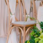 Chic reception setting with draped chairs and lush flowers.