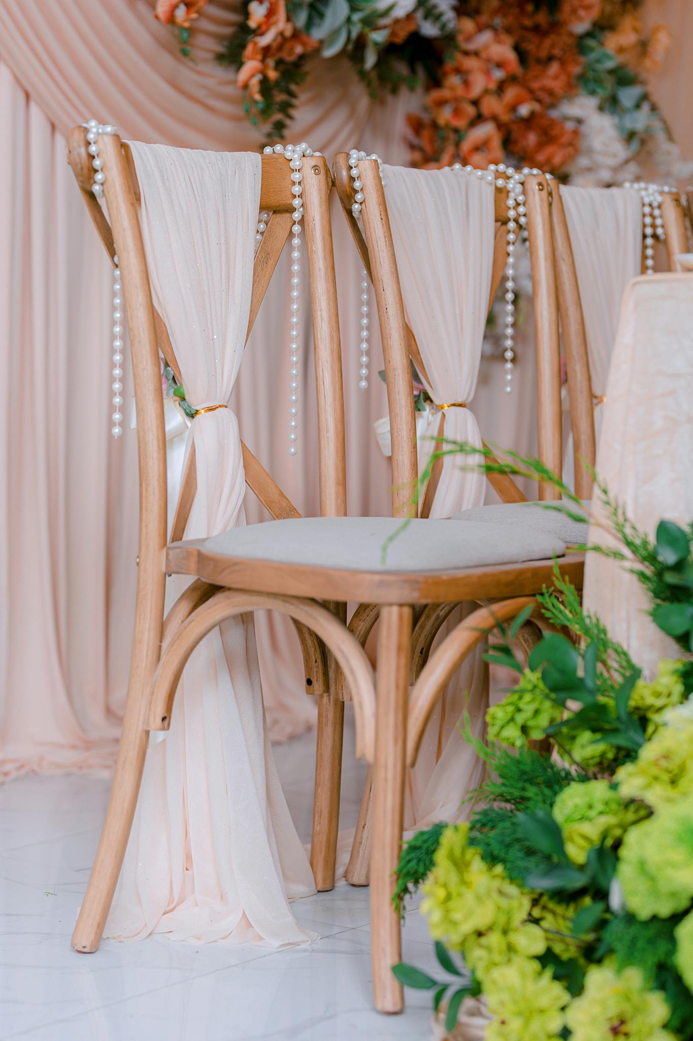 Chic reception setting with draped chairs and lush flowers.