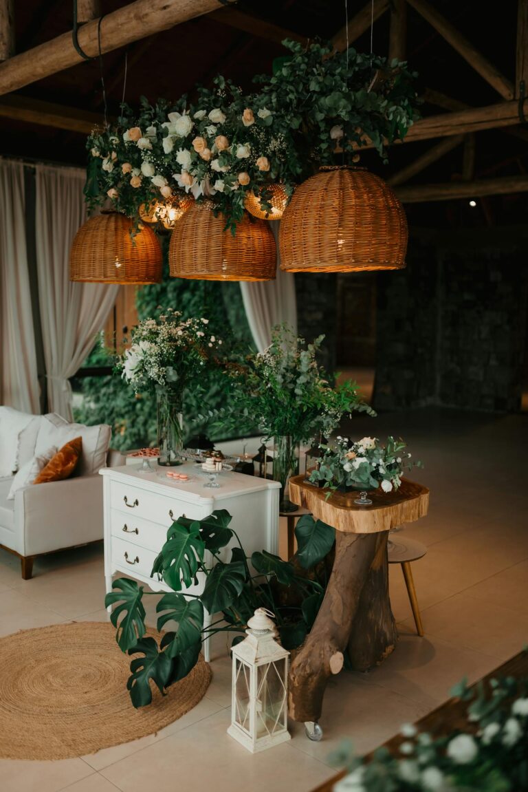 Cozy indoor rustic wedding setup with lush greenery and hanging wicker lights.