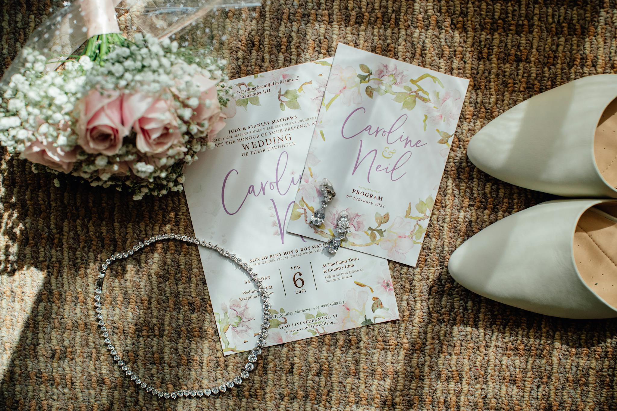 Elegant wedding flat lay featuring invitations, flowers, shoes, and jewelry on a textured surface.